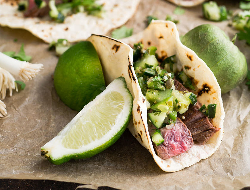 Tacos de carne asada con diversos complementos en un negocio de comida sonorense.