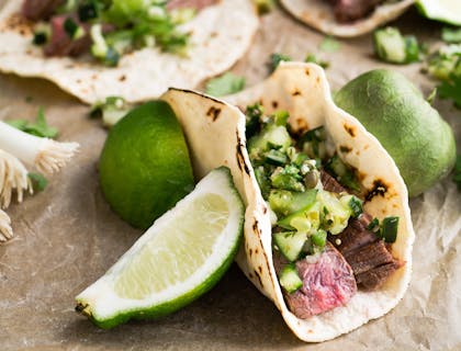 Tacos de carne asada con diversos complementos en un negocio de comida sonorense.