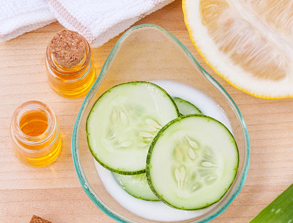 Rodajas de pepino dentro de un bowl junto a una mitad de lima, un frasco con miel y trozos de sábila en un negocio de cosméticos naturales.
