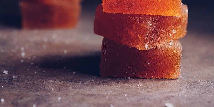 Seis trozos de dulce de membrillo en dos columnas sobre una superficie gris con un fondo negro en un negocio de dulce de membrillo.