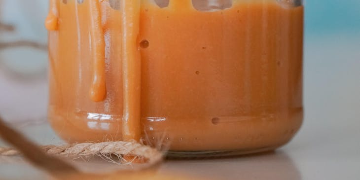 Un frasco de vidrio con dulce de leche sobre una mesa de madera en un negocio de dulce de leche.
