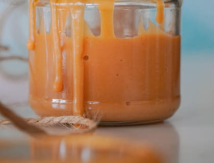 Un frasco de vidrio con dulce de leche sobre una mesa de madera en un negocio de dulce de leche.