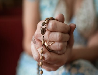 Una mujer tomando entre sus manos un escapulario en un negocio de escapularios