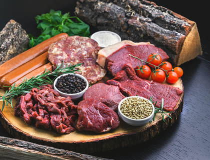 carnes y embutidos crudos sobre un plato junto a demás ingredientes y aderezos para preparar fritanga en un negocio de fritanga