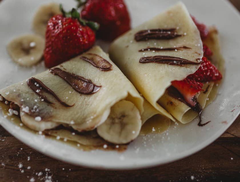 Crepas dulces sobre un plato con trozos de plátano y fresas en un negocio de gusgueras.