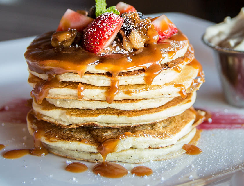 Un plato con hot cakes con cajeta, frutos rojos y crema batida en un negocio de hot cakes.