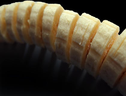 Una banana en trozos para cocinar jibaritos sobre un fondo negro en un negocio de jibaritos.