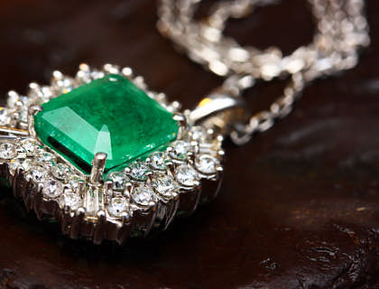 Arete de oro blanco con pequeños diamantes alrededor de una gema de jade en el centro sobre un fondo oscuro en un negocio de joyas de jade.