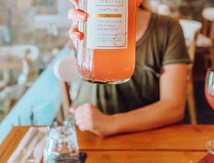 Una mujer sosteniendo una botella de jugo de zanahoria fresco en un negocio de jugos.