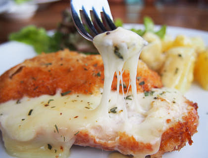 Una milanesa napolitana siendo comida por un comensal en un restaurante.