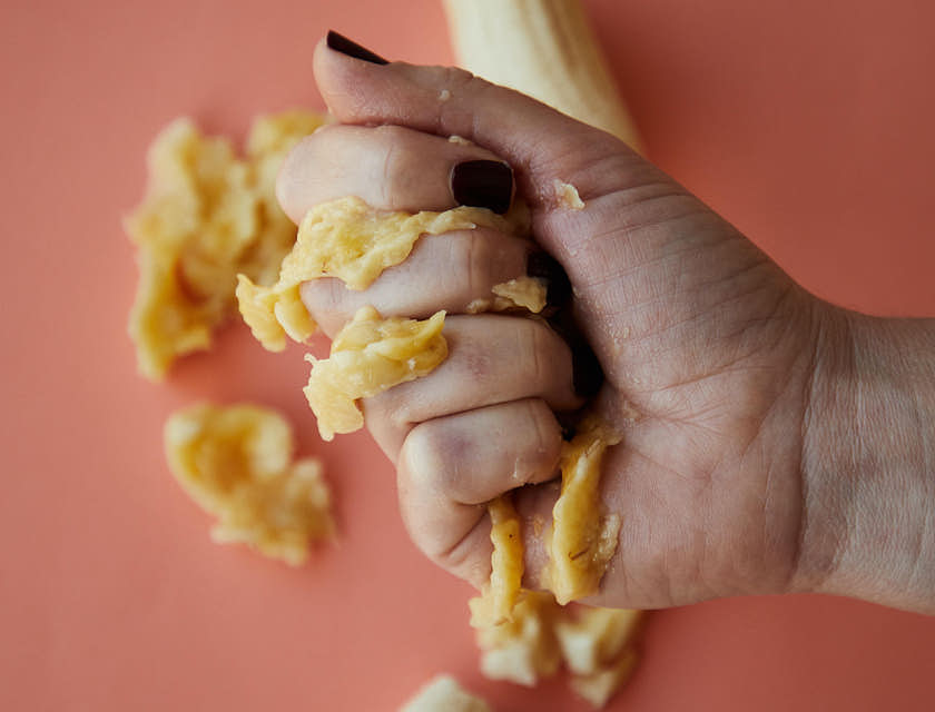 La mano de una persona aplastando un plátano en un negocio de mofongo.