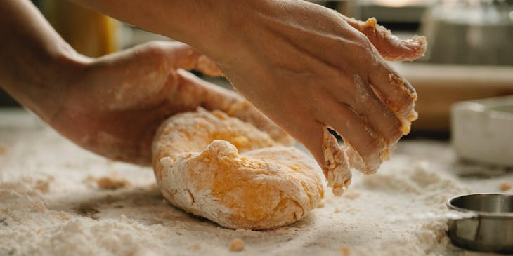Una persona amasando una bola de masa para hojaldre para preparar pastelitos criollos.