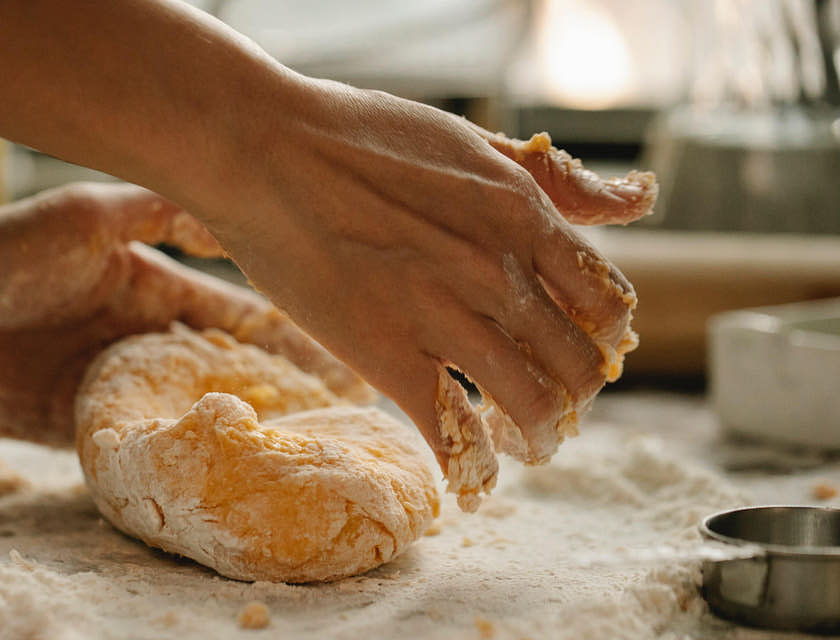 una persona amasando una bola de masa para hojaldre para preparar pastelitos criollos