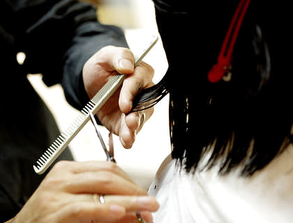 Hombre cortando el pelo a una mujer en un negocio de peluquería a domicilio.