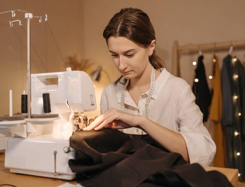 Un sastre cosiendo una prenda con una máquina de coser.