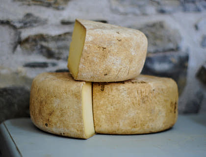 Una rueda de queso de tafí cortada en tres partes sobre un aparador en un negocio de queso de tafí.