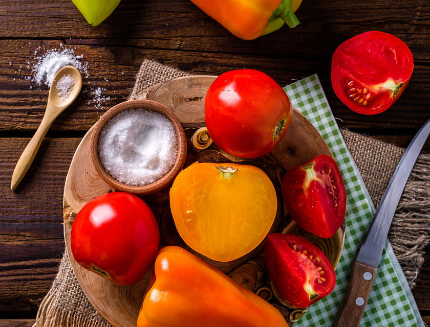 Pimentón, tomate y un cuenco con sal sobre una mesa de madera en un negocio de quiquirimichi.
