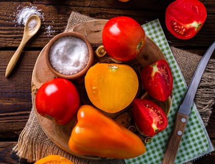 Pimentón, tomate y un cuenco con sal sobre una mesa de madera en un negocio de quiquirimichi.