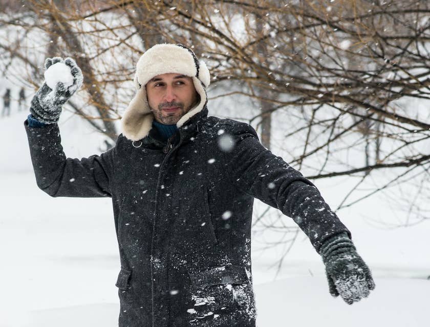 Un hombre lanzando una bola de nieve afuera de un negocio de ropa para invierno