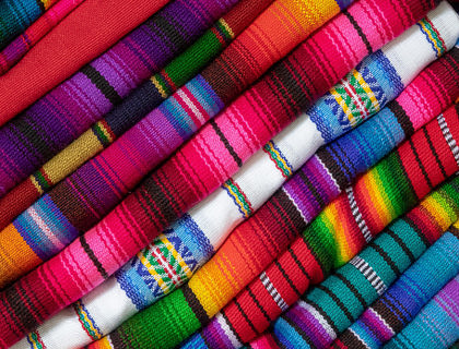 Sarapes de varios estilos y colores doblados y acomodados en un negocio de sarapes.