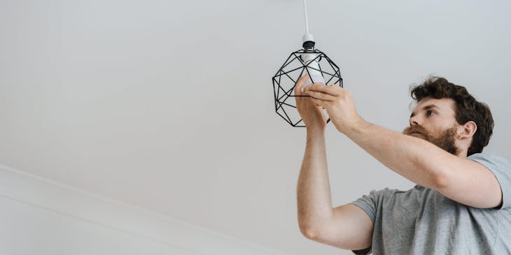 A home services employee installing a ceiling light.