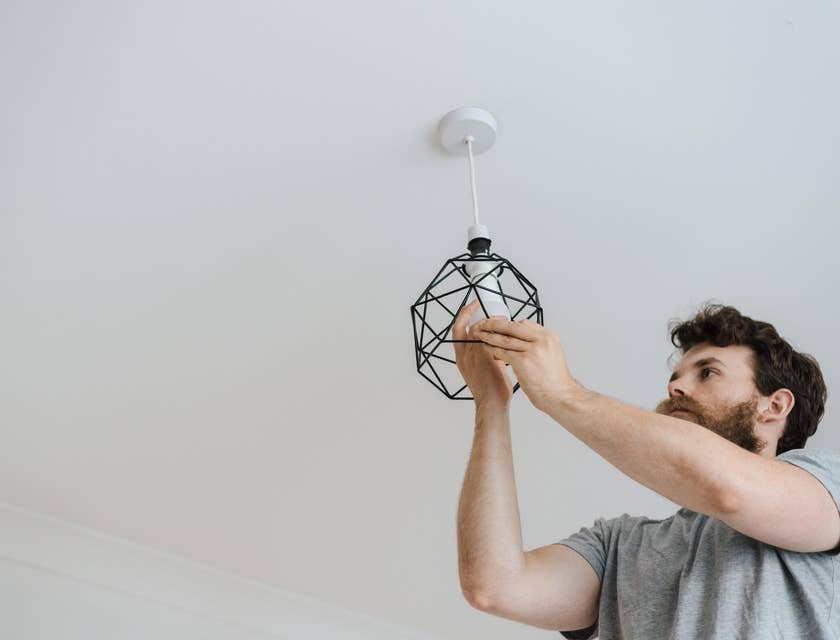 Un impiegato di un'azienda di servizi domestici che cambia una lampadina in una lampada a soffitto.