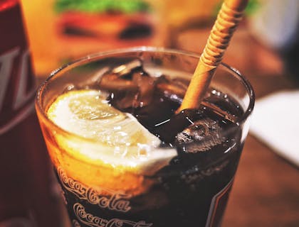 Una soda refrescante en un vaso de vidrio con hielos, una rodaja de limón y un popote en un negocio de soda de coco.