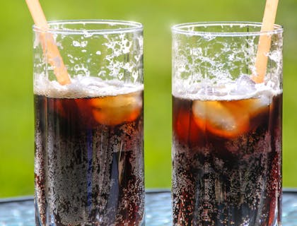 Dos vasos con soda, hielos y popotes en un negocio de sodas.