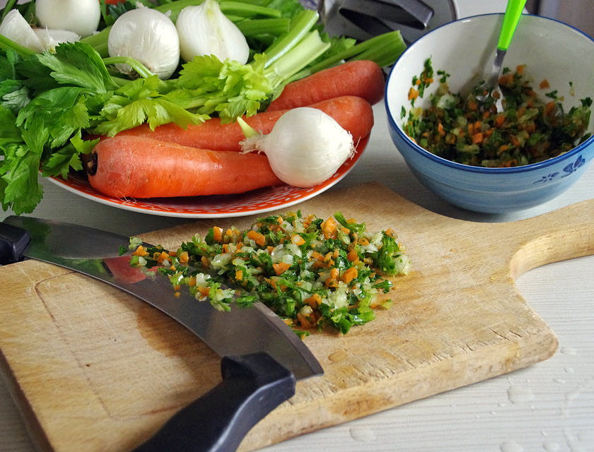 Una tabla de madera con sofrito recién hecho a un lado de un bowl lleno de sofrito en un negocio de sofrito.