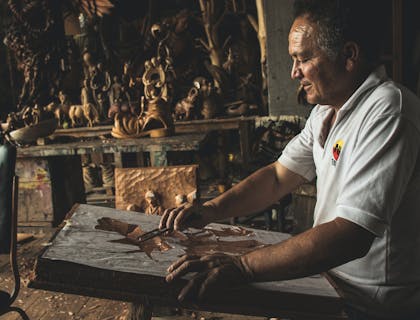 Un escultor trabajando en madera en el taller de un negocio de talla de madera.