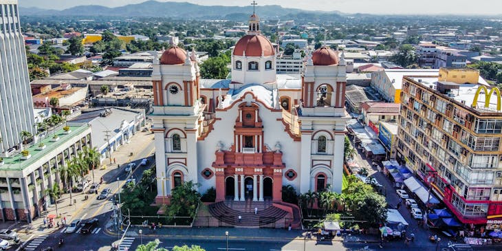 Vista de la catedral metropolitana de San Pedro Sula con la montaña de coca cola sign al fondo en un negocio de tours a coca cola sign San Pedro Sula.
