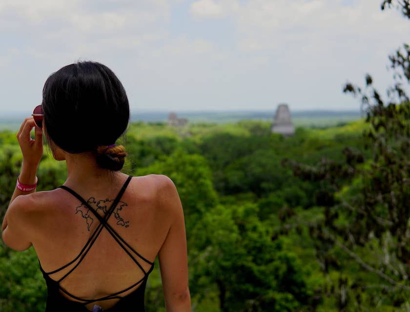 Mujer con un tatuaje en la espalda observando la selva maya en un negocio de tours a mMyan Eden.