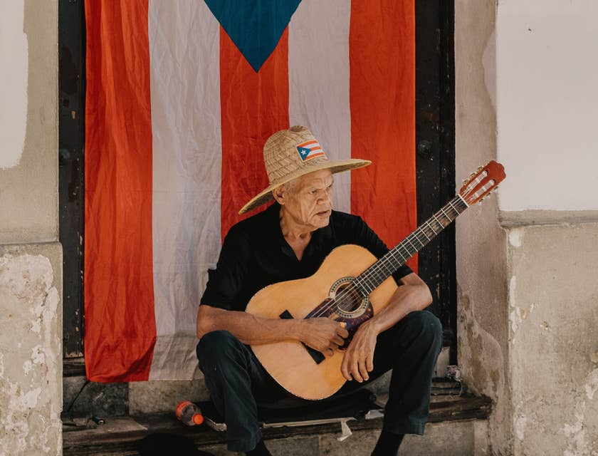 Un hombre con una guitarra frente a una bandera de Puerto Rico en un negocio de trifongo.
