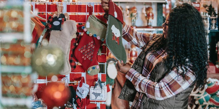 Una mujer eligiendo adornos navideños en un negocio de variedades.