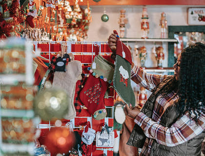 Una mujer eligiendo adornos navideños en un negocio de variedades.