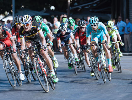 Grupo de ciclistas pedaleando en una carrera para una página deportiva.