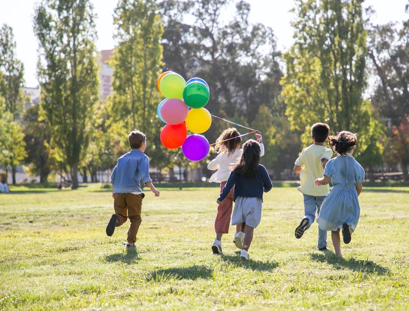 Un grupo de cinco niños jugando con unos globos en un parque recreativo.