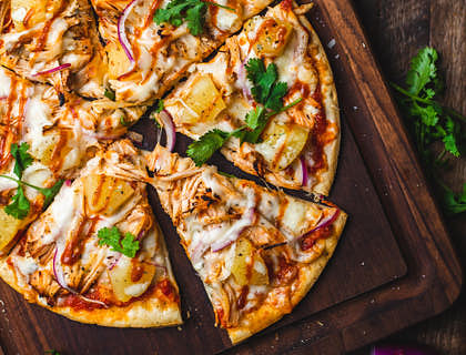 Una pizza completa sobre una tabla de madera oscura en una pizzería de fugazzeta.