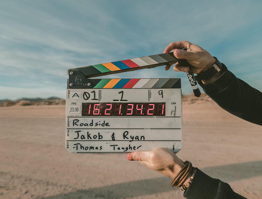 Una claqueta a punto de ser cerrada por un asistente de producción en una locación de grabación por parte de una productora de cine.