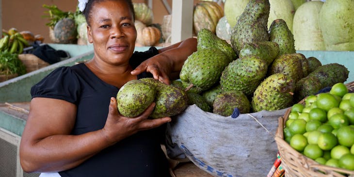 Una mujer haitiana mostrando la fruta de su mercado que se comerá en un restaurante haitiano.