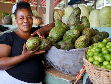 Una mujer haitiana mostrando la fruta de su mercado que se comerá en un restaurante haitiano.