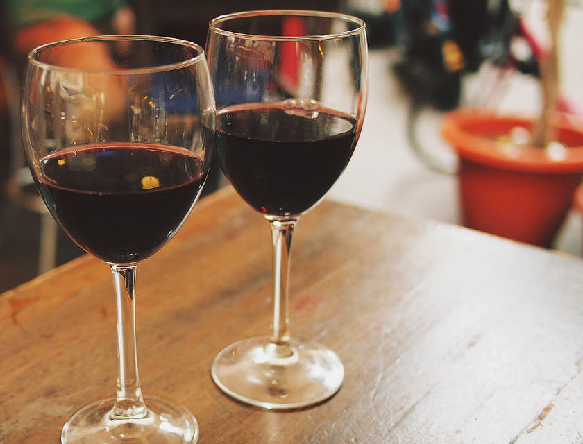 Dos copas servidas con vino tinto sobre una mesa de madera en un restaurante andaluz.