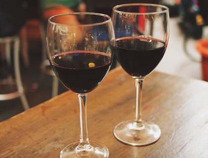 Dos copas servidas con vino tinto sobre una mesa de madera en un restaurante andaluz.