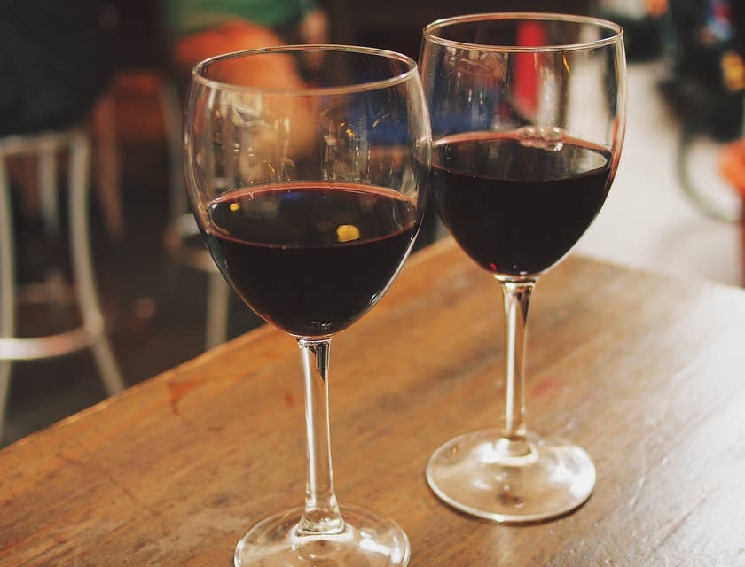 Dos copas servidas con vino tinto sobre una mesa de madera en un restaurante andaluz.