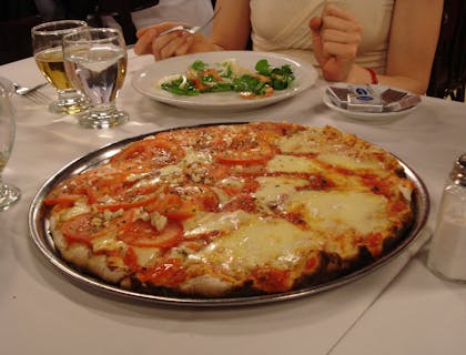 una pizza argentina recién salida del horno en medio de una mesa en un restaurante de pizza argentina