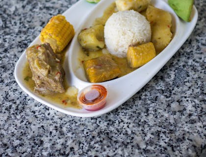 Plato de sancocho servido en una vajilla blanca sobre una mesa en un restaurante de sancocho.