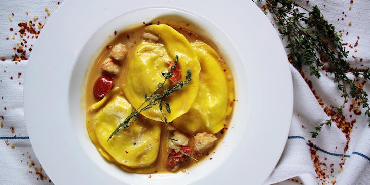 Tres sorrentinos servidos con salsa de tomate en un plato de cerámica blanca en un restaurante de sorrentinos