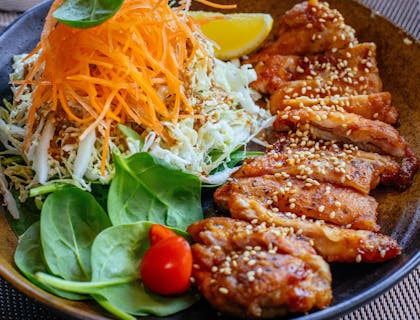 Un plato con ensalada, aderezo y pollo al ajonjolí en un restaurante pollotariano.