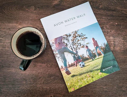 Una revista deportiva a un lado de un café negro sobre una mesa de madera oscura.