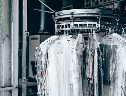 Camisas y pantalones embolsados y colgando de una banda giratoria en un servicio de lavaseco.